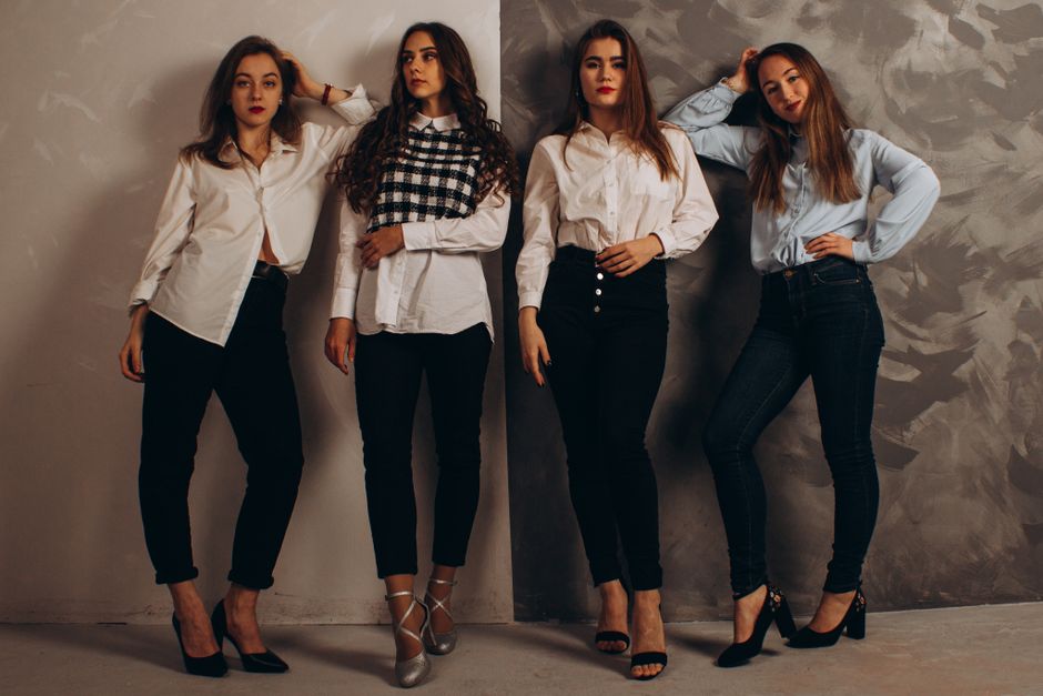 A group of fashionable women posing in a studio wearing smart casual outfits.