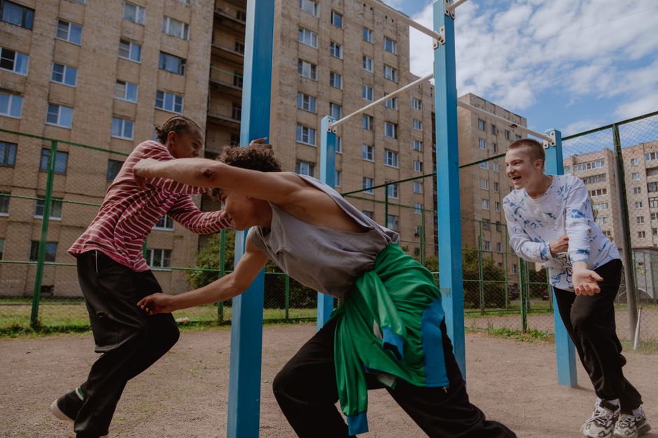 A joyful group of teenagers having fun at an urban playground beneath a blue sky.