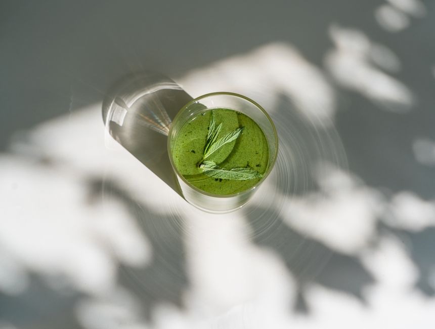 Top view of a refreshing green matcha drink with mint leaves, casting shadows.