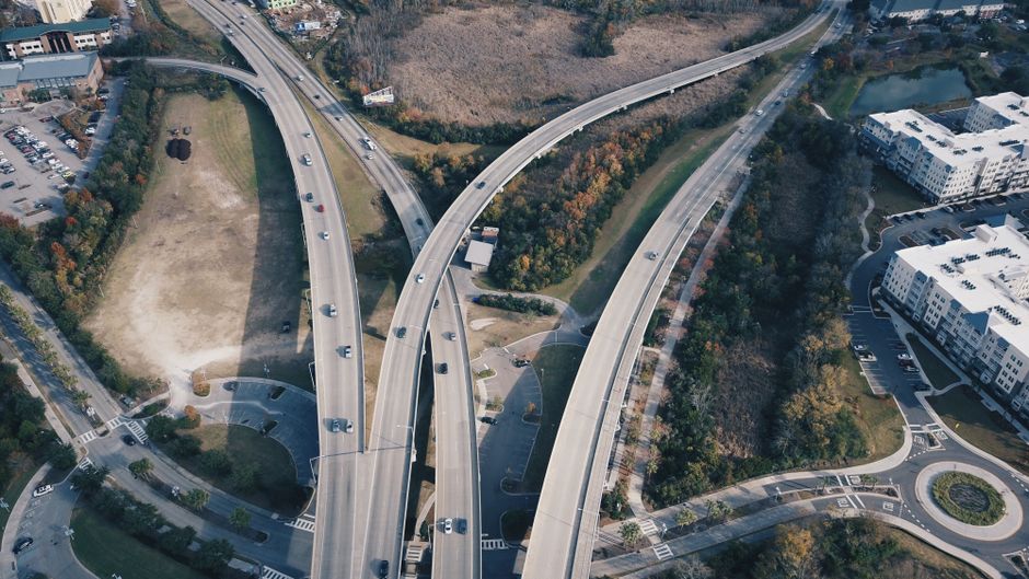 Aerial view of intersecting highways with light traffic and surrounding greenery.