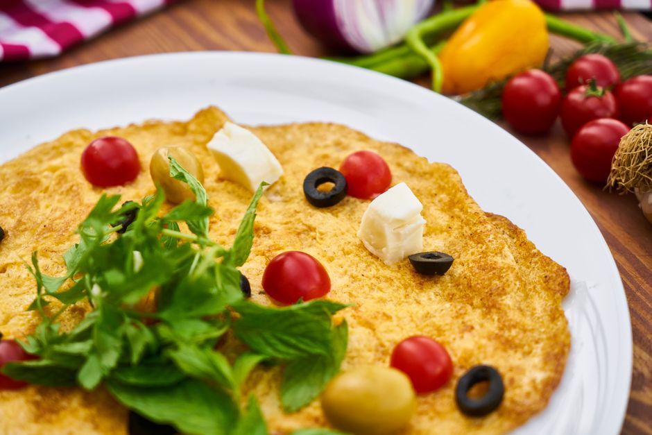 Delicious and vibrant omelette topped with fresh tomatoes, olives, and cheese on a plate.