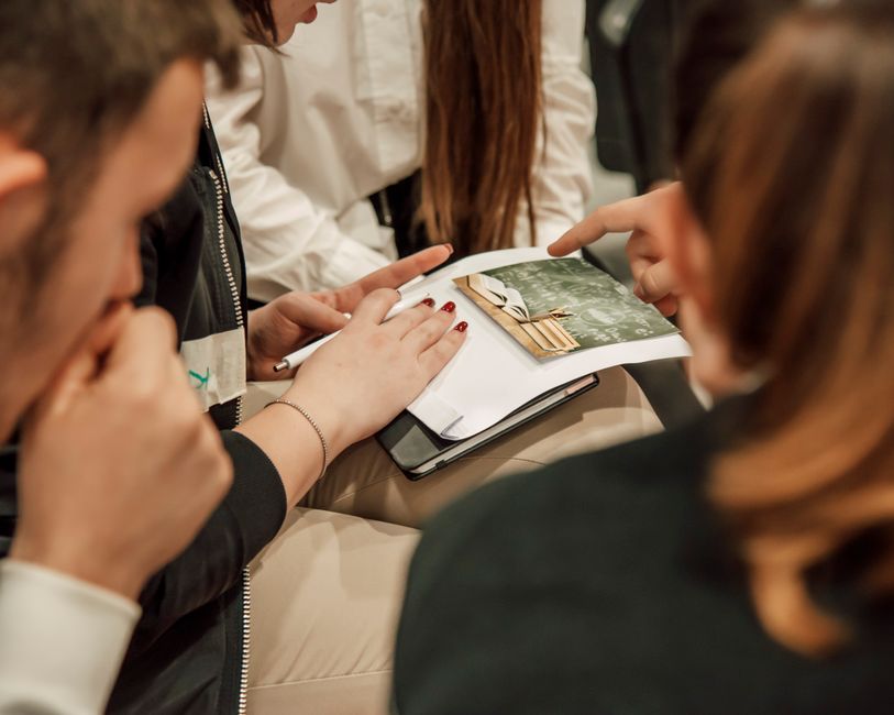 Close-up of people engaged in a group study session, sharing ideas with a book.