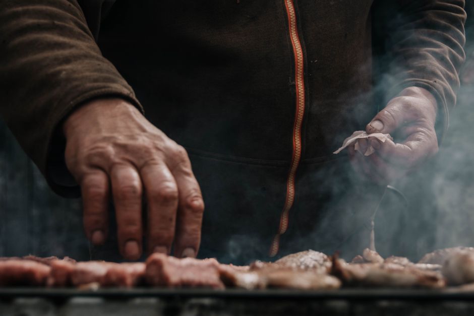 Man grilling meat outdoors with smoke rising, Belgrade, Serbia.