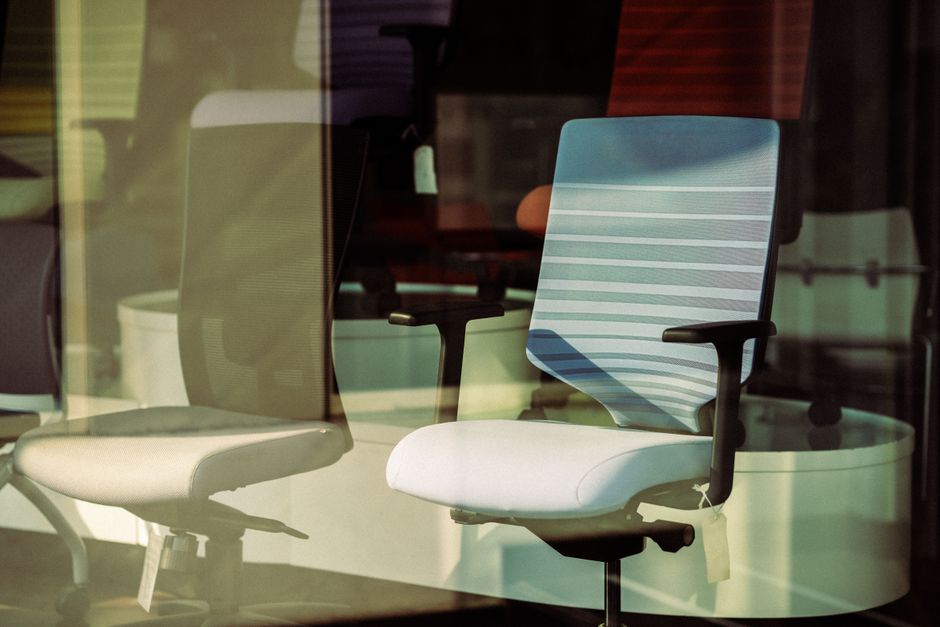 Contemporary office chairs displayed behind glass, offering modern ergonomic solutions for workspace.