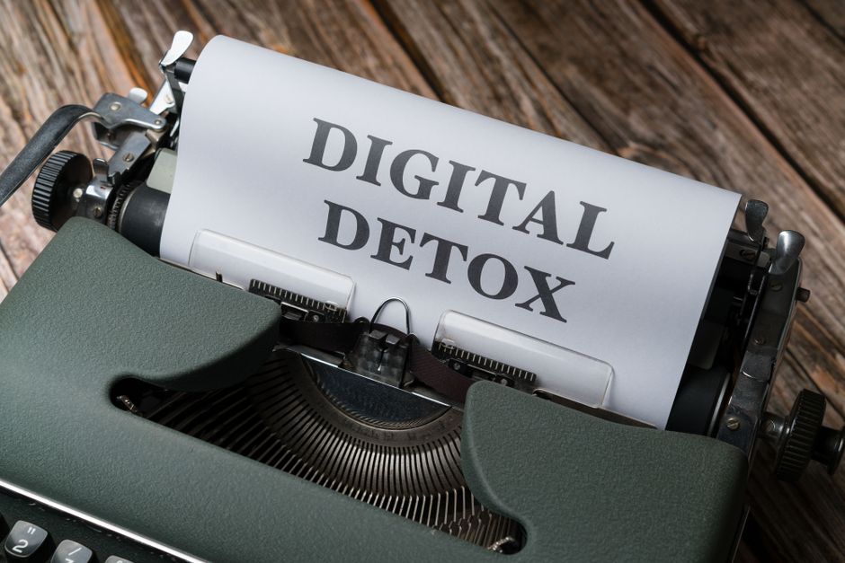 An overhead view of a typewriter printing 'Digital Detox' on wooden background.