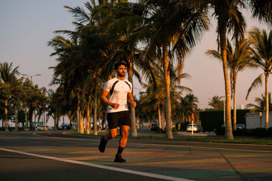 A male jogger enjoys an early morning run along a palm-lined road in Jeddah, Saudi Arabia.