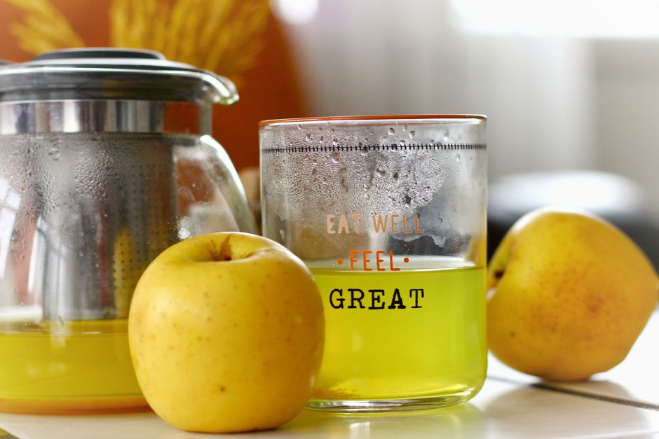 Close-up of fresh apple juice and a teapot with steamed apples on a kitchen counter.