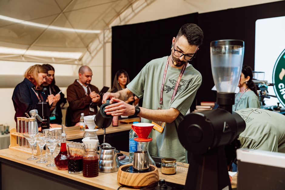 Barista preparing coffee at a festival in Baku, Azerbaijan with audience watching.
