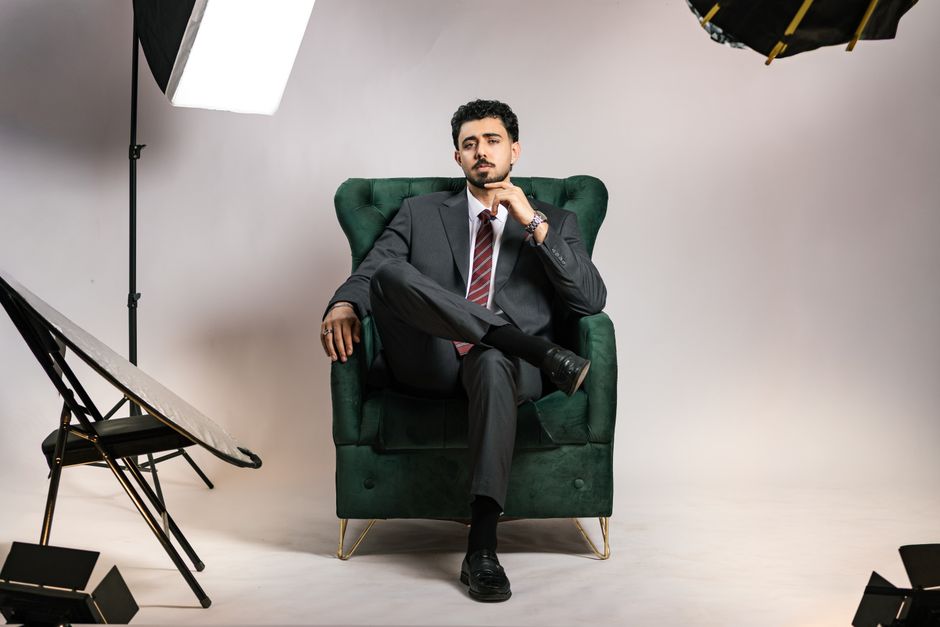A confident businessman in a suit poses in a professional studio setting.