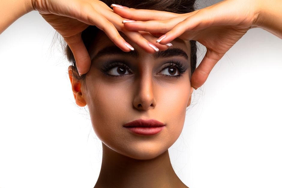 Close-up portrait of a woman with natural makeup, highlighting expressive eyes and flawless skin.