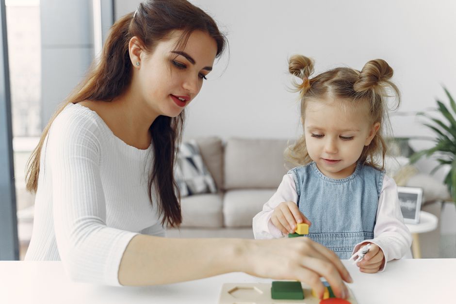 A mother and daughter bond while playing with educational toys indoors.