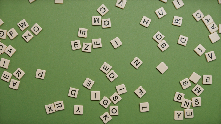 Scattered alphabet tiles on a green background, perfect for word games and educational themes.