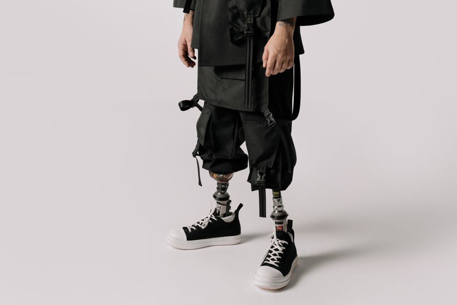 Close-up of a person wearing prosthetic legs, stylishly dressed in a studio setting, focusing on modern fashion.