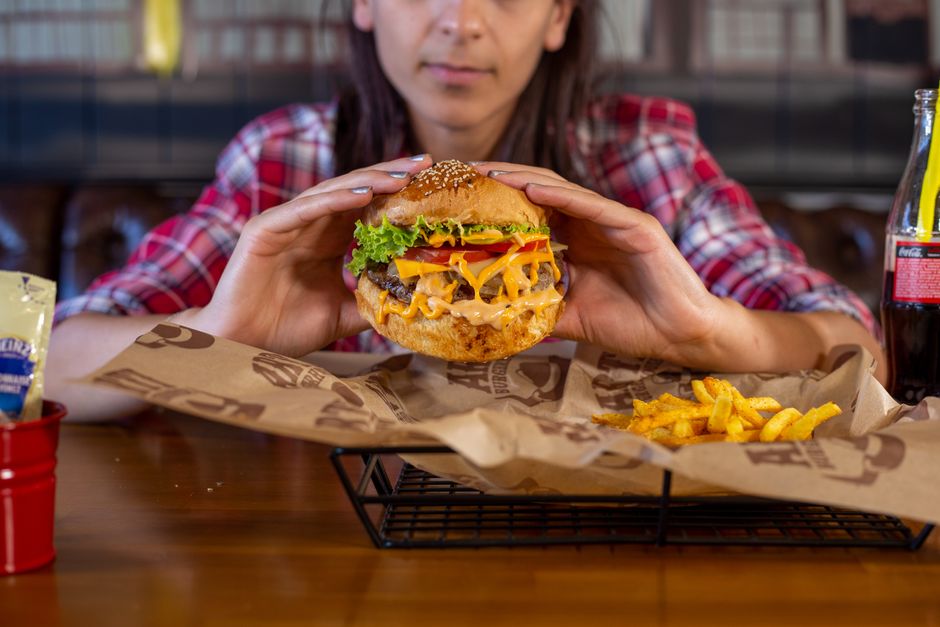 Close-up of a cheeseburger with fries, held by a person, perfect for food photography.