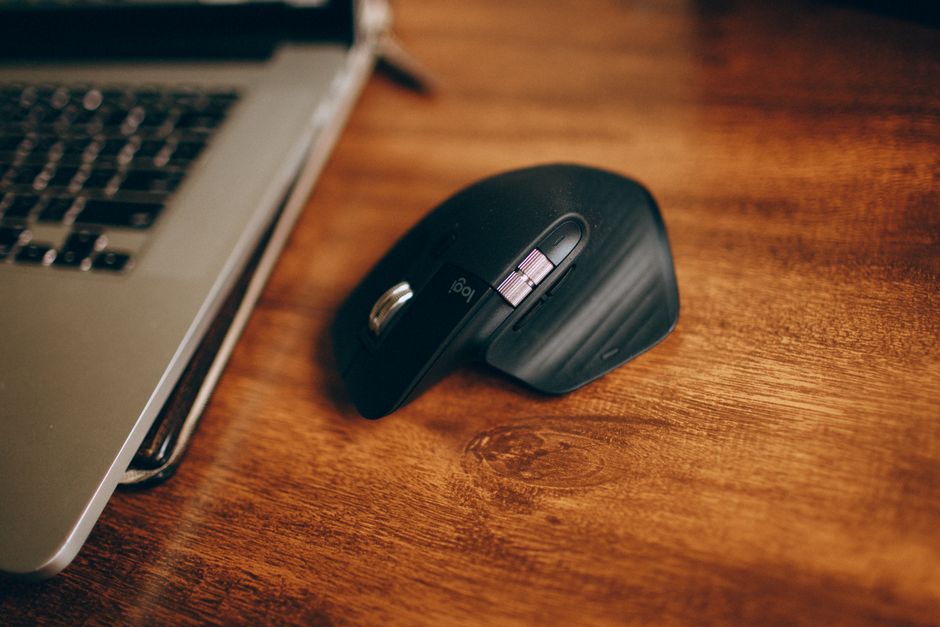 Stylish wireless mouse next to laptop on a wooden table, perfect for modern workspace setups.