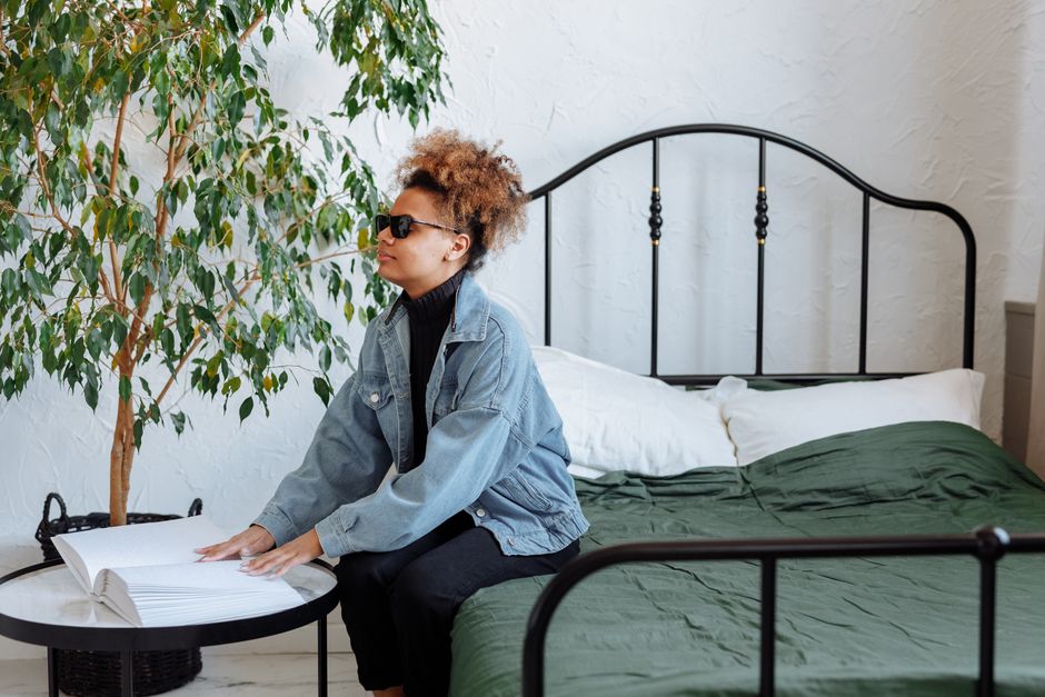 Woman reading a braille book at home, embracing calmness and sensory perception.