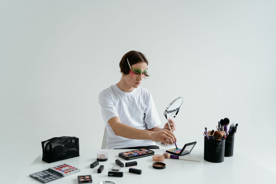 A person using vibrant eyeshadow and makeup brushes for a creative expression indoors.