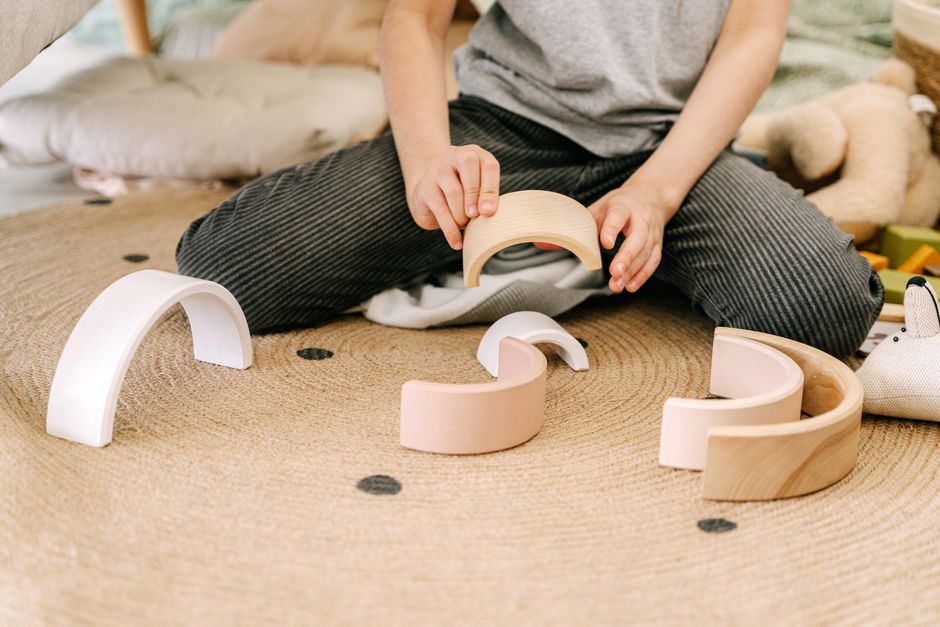 A child engaging in play with wooden arched blocks, enhancing motor skills and creativity.